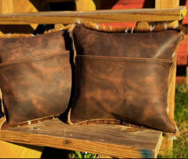 Two brown leather pillows on a wooden surface with a blurred background